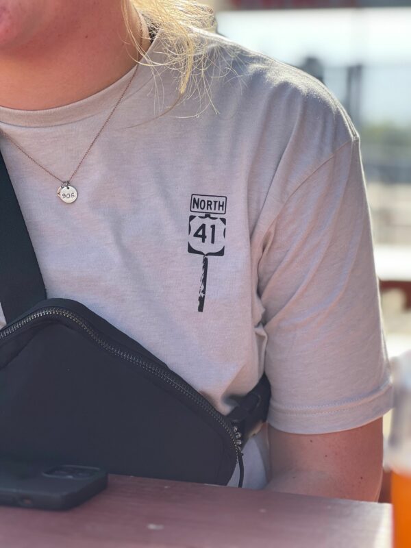 image of a girl with a 906 necklace wearing a tan tee with a shoulder bag