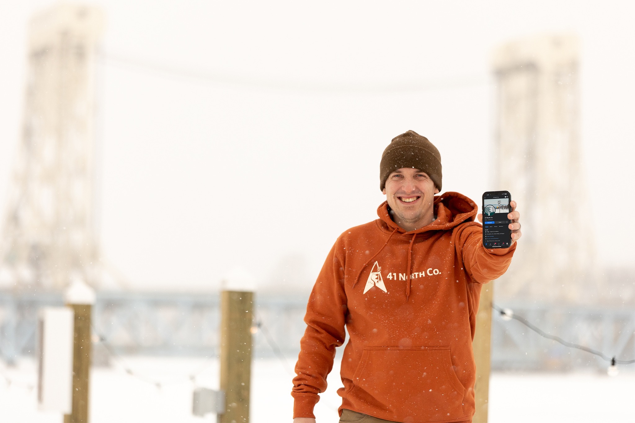 Man holding cellphone out in front of a bridge