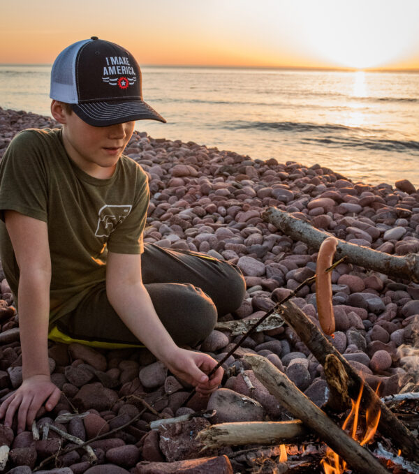 image of young boy roasting a hotdog on a rocky beach next to Lake Superior