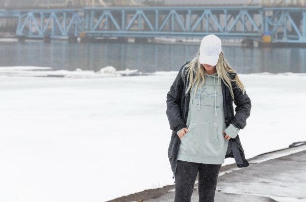 Young lady wearing a blue hoodie with a jacket in front of the Portage Lake lift bridge