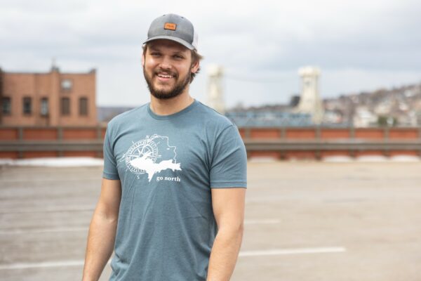 Young man wearing a blue 41 North Co tee standing on a parking deck