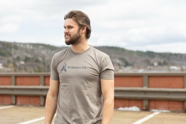 Young man wearing a gray tee with the 41 North Co logo on the chest